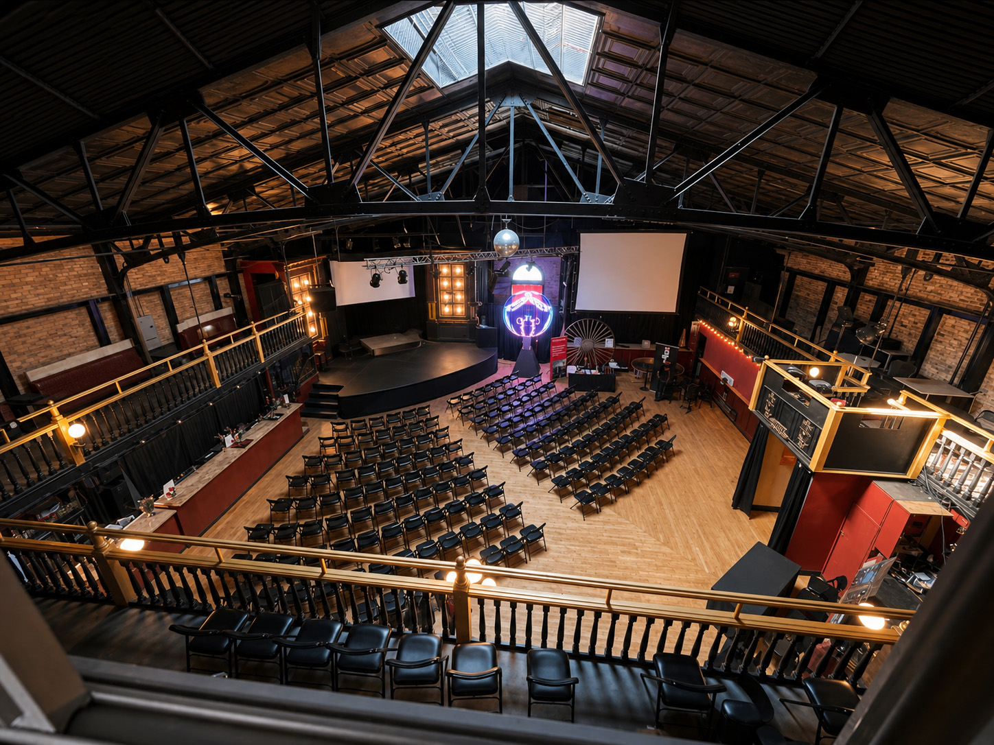 Wide view of the stage, mezzanine balcony, dance floor, and main bar set for a corporate event